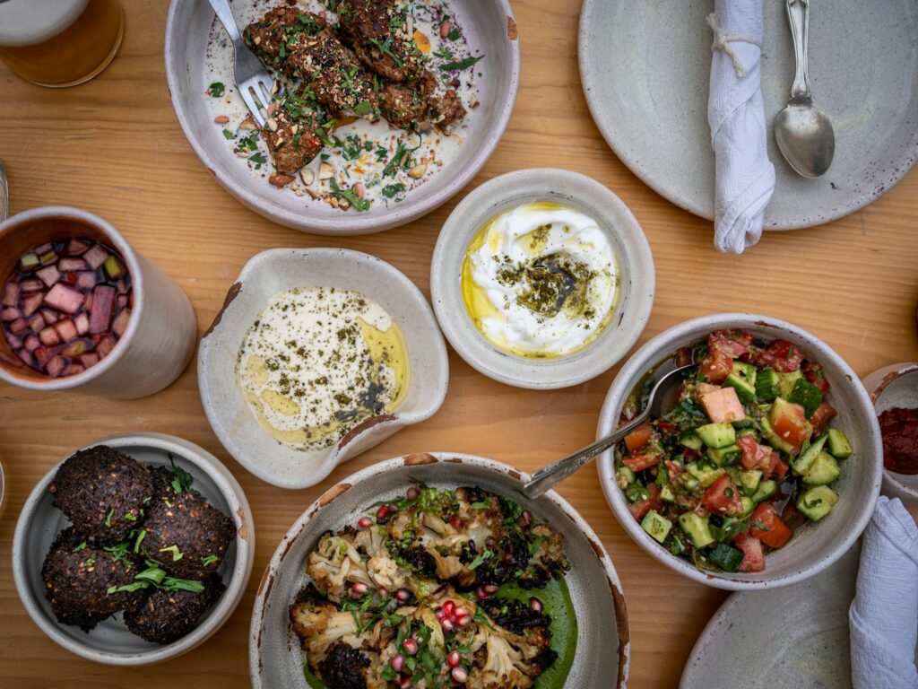A wooden table topped with bowls of Mediterranean food