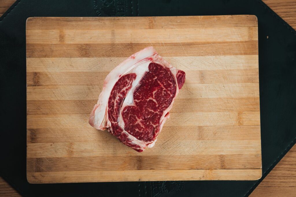 Raw ribeye steak on a wooden cutting board, representing the carnivore and keto diet comparison